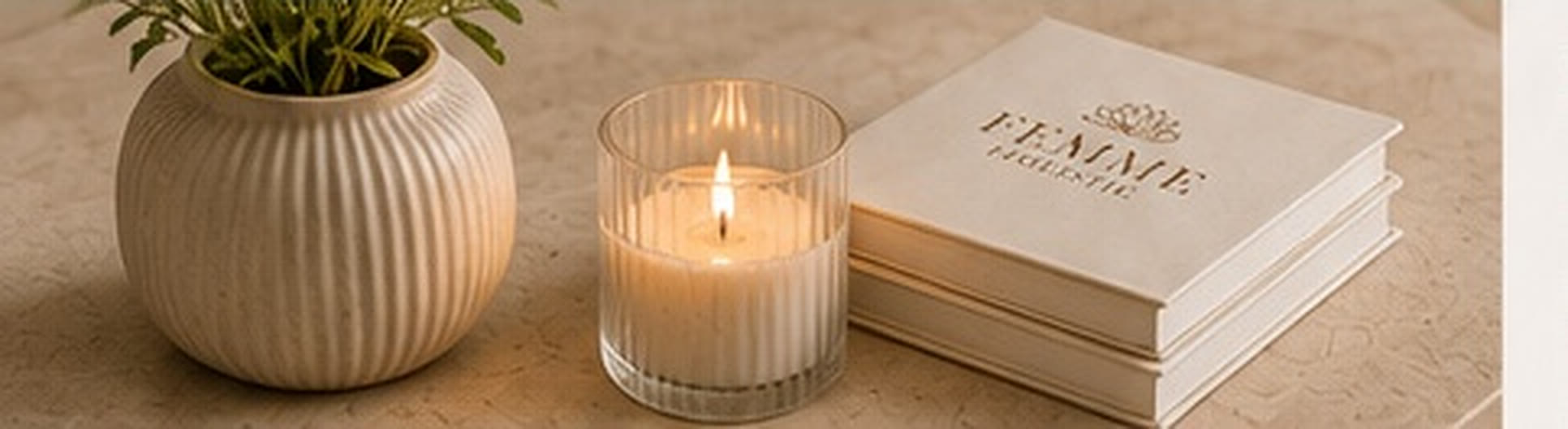 Plant, brandende kaars en Femme Holistic-boeken op een lichte tafel